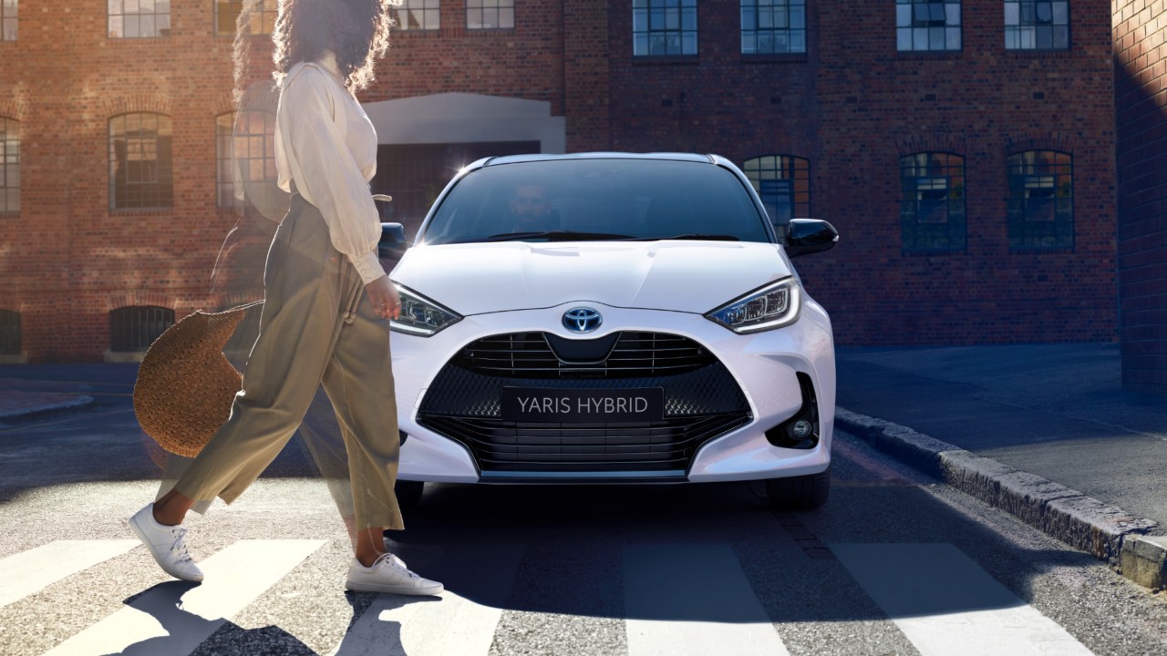 Toyota yaris hybrid with a woman walking past
