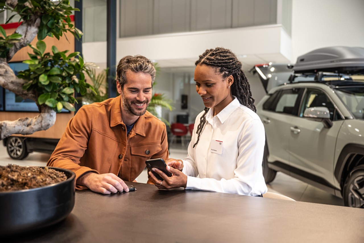 a Toyota employee showing a customer something on a phone