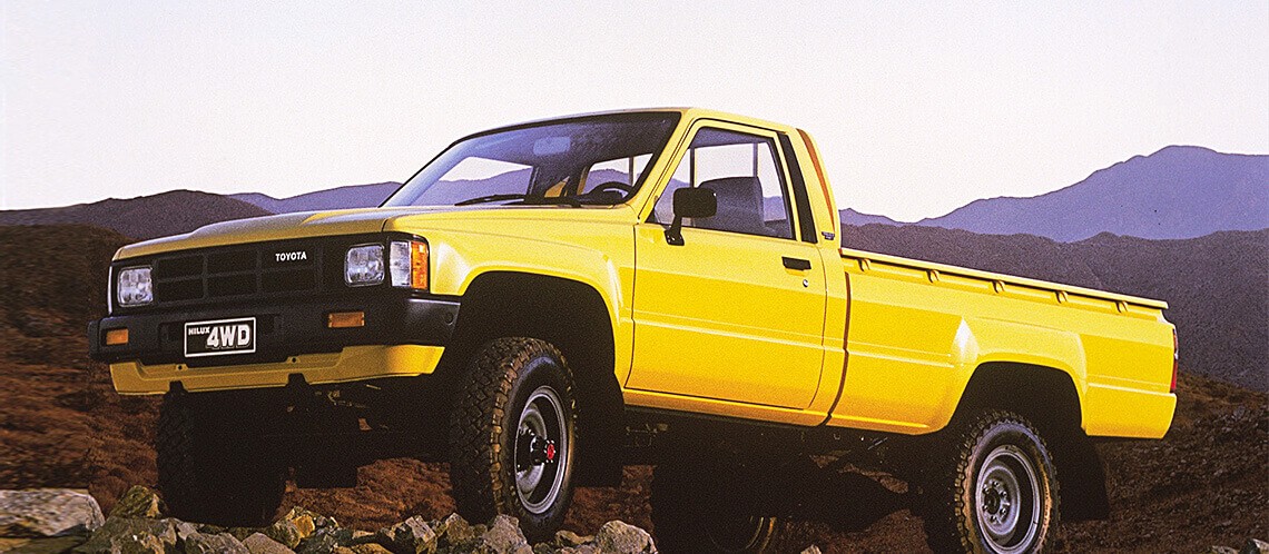 yellow Toyota Hilux parked on rocks