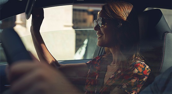 Smiling girl in sunglasses looking in mirror in Toyota passenger seat