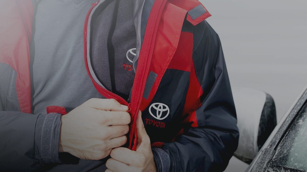 Close up of a man zipping up a Toyota coat